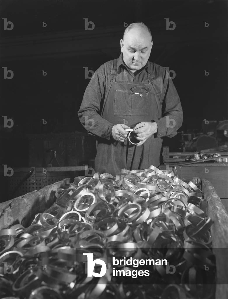 Conversion, copper and brass processing, gaging copper rotating bands, these copper rotating bands fit the serrations inside gun barrels and make the projectile rotate as it is shot from the gun. This man is checking the diameter of bands, Chase Copper and Brass Company, Euclid, Ohio, photograph by Alfred T. Palmer, February, 1942