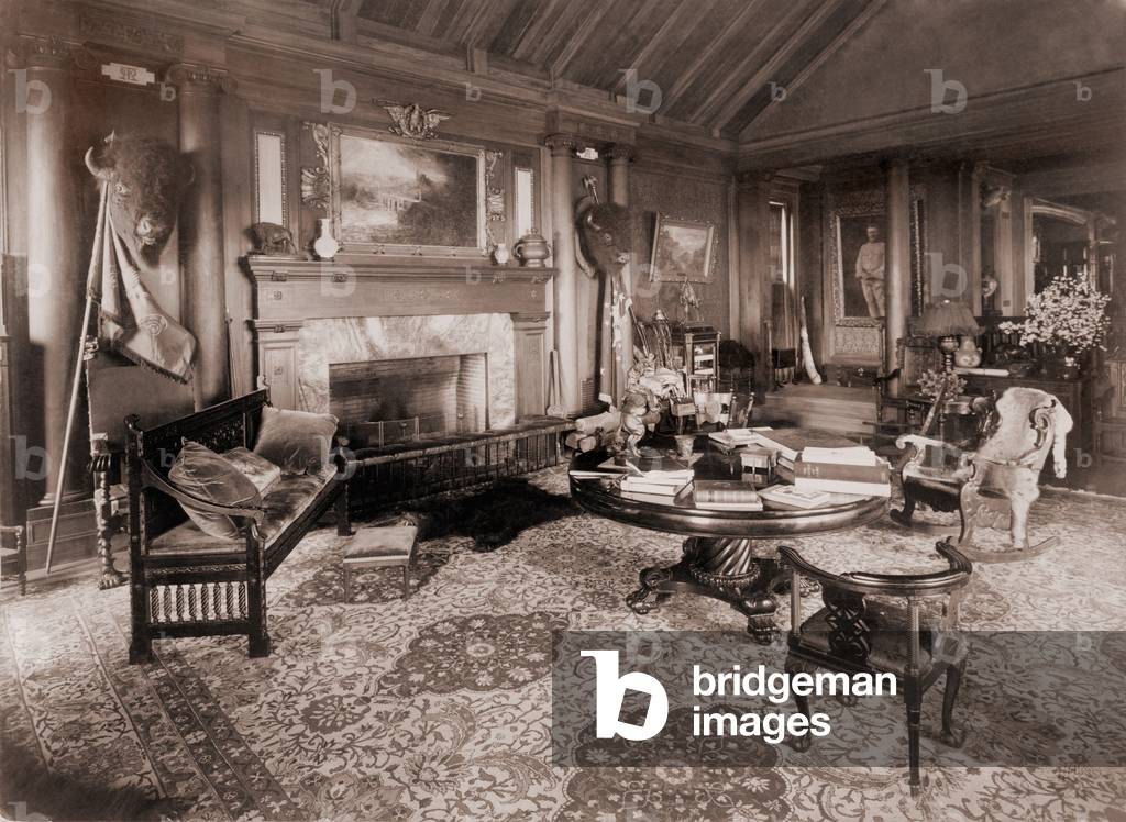 Trophy room at Sagamore Hill, summer home of President Theodore Roosevelt, with bison heads, bearskin rug, and battle standards. c. 1910