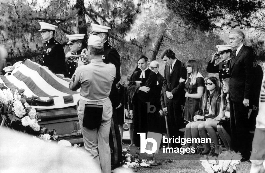 A Marine bugler plays Taps at the funeral of RONALD McLEAN STEWART, as REV. DR. JAMES T. MATHIEU, JOHN FORD, MICHAEL McLEAN STEWART, KELLY STEWART, JUDY STEWART and JAMES STEWART look on, 6/17/69