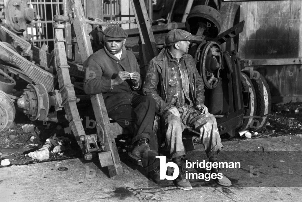 Men sitting on parts of truck in junkyard, South Side of Chicago, Illinois, photograph by Lee Russell, April, 1941