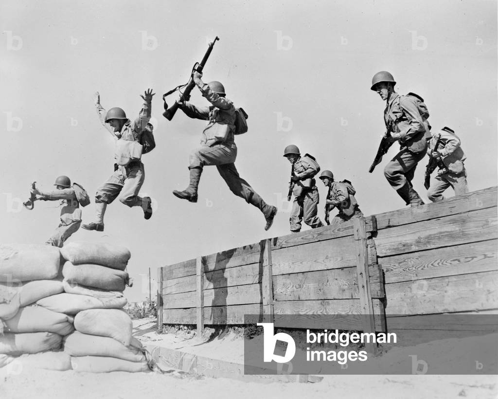World War II, original caption: A hard-running leap takes these artillerymen over one of the obstacles on the course at the anti-aircraft training center. Here we see the different phases of the jump; one man has just landed on the sandbags; two are in the air; and another man is gathering himself for the spring across', Camp Edwards, Massachusetts, 1942