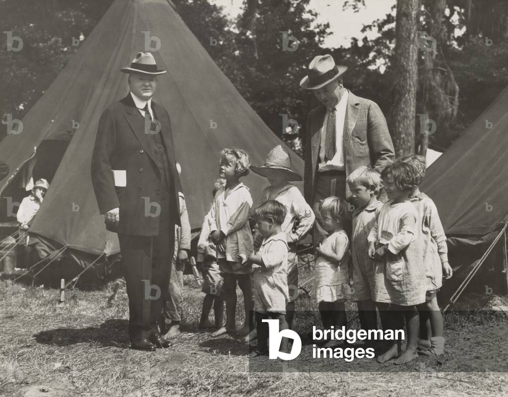 Herbert Hoover with girls and boys at a tent camp during the Great Mississippi River Flood in 1927. The worst effected states were Arkansas, Mississippi, and Louisiana. Hoover, then Sec. of Commerce, was named by President Coolidge to coordinate flood relief with the American Red Cross