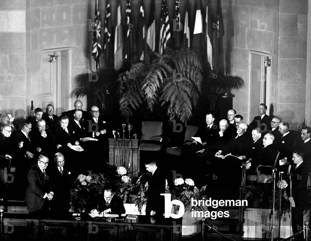 NATO, President Truman and V.P. Barkley, look on as Secretary of the State Dean Acheson signs the North Atlantic Treaty signing ceremony in Washington D.C., John W. Foley, State Dept. Treaty advisor, is on the platform, April, 1949