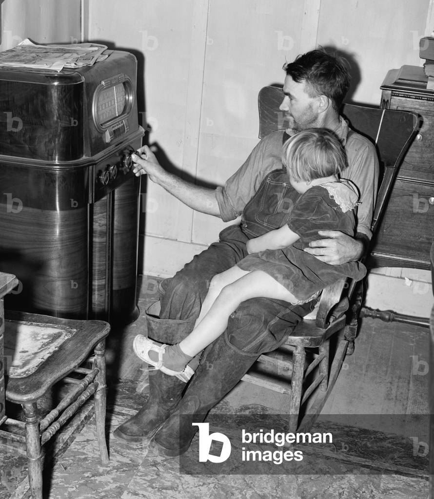 John Frost and daughter listening to their radio, a luxury item in their modest home for a family of seven. Frost was the owner of a struggling farm in Northern California that produced milk, turkeys, and hogs. 1940 photograph by Russell Lee