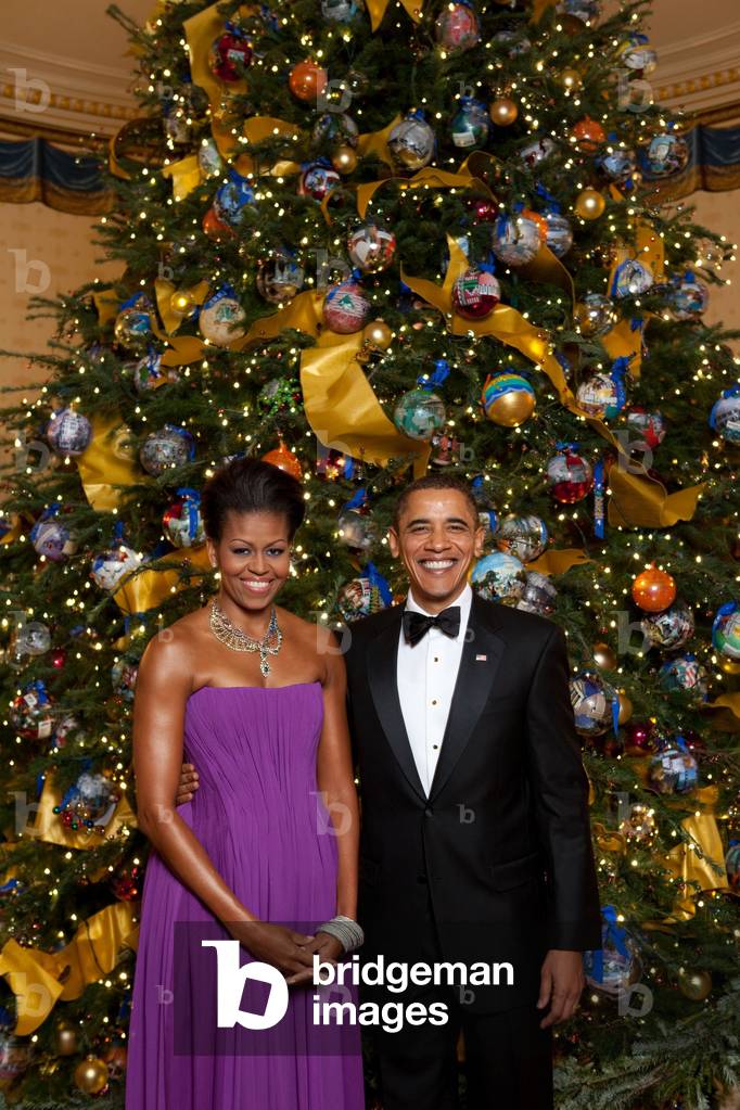 President and Michelle Obama pose in front of the Official White House Christmas Tree Dec. 6 2009. Michelle wears a purple pleated chiffon dress with a corset lacing back by Peter Soronen with Tom Binns necklace.,