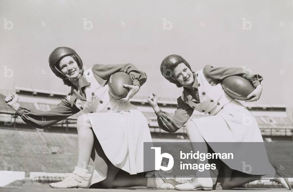 Two cheerleaders from Tulane University, Oct. 5, 1942. They are wearing football helmets and holding footballs.