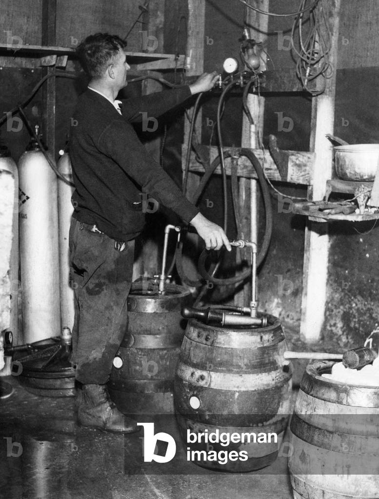 A 'brewmeister' fills kegs at a bootleg brewery during Prohibition, 1933