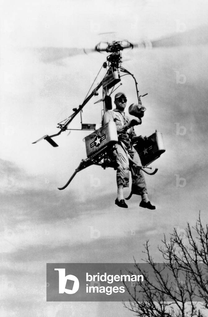 Rocket powered personal helicopter. Called the 'Pinwheel', it was a strap-on-the-back model and folded to the size of a phone booth. Pilot Dick Whitehead prepares to land on his own two feet. April 15, 1957