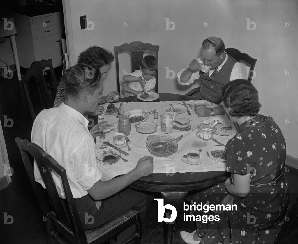 Family dinner in Greenbelt, Maryland, federally subsidized community, Dec. 1937. The modest meal which includes white bread and beans served on small plates
