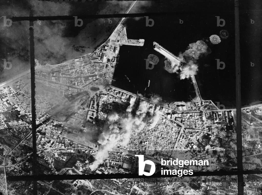 World War II, original caption: 'The deadly marksmanship of the United States Army Air Force bombers is graphically illustrated in this picture just received from North Afric. It shows direct hits on harbor warehouses and terminals and a pierhead at Sousse, the important Axis-held Mediterranean seaport in Tunisia', c.1943
