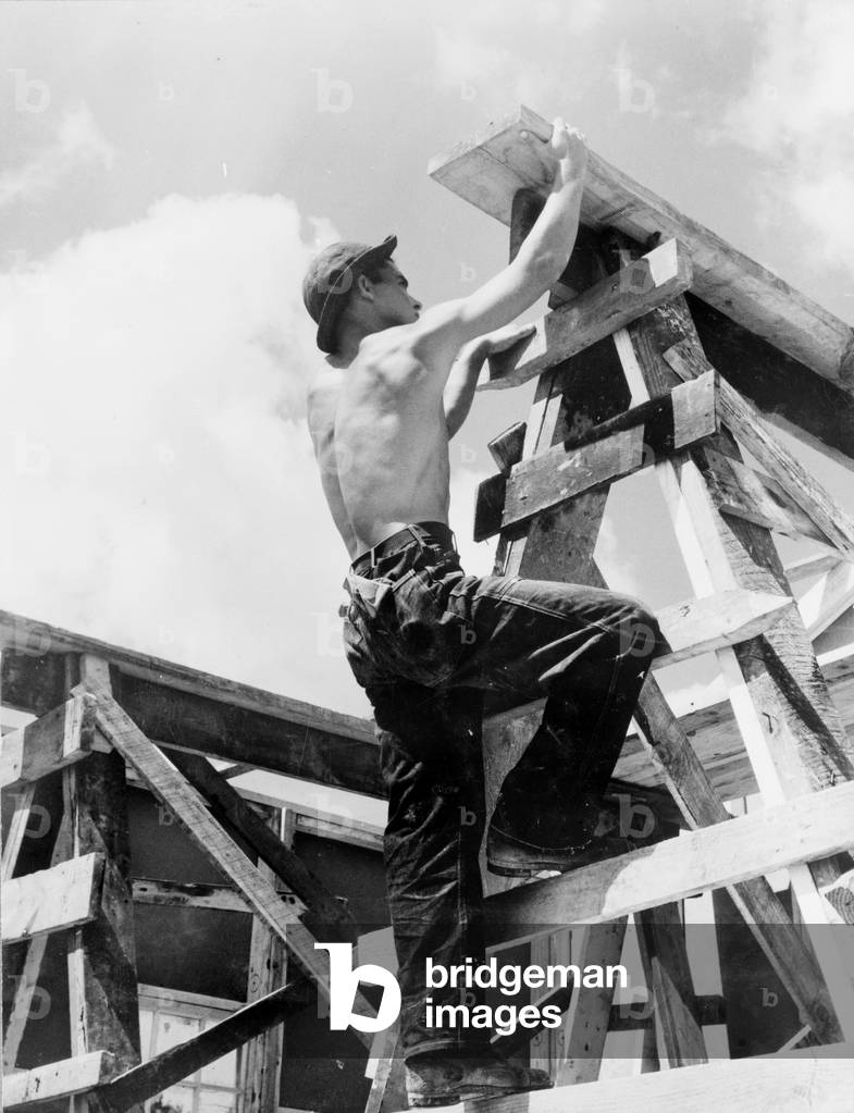 Civilian Conservation Corps at work. Enrollee William L. Cross climbing up on a scaffold erected for assembling a prefabricated building to be a camp work shop, United States Resettlement Administration, Appalachia, Virginia, 1935-1942