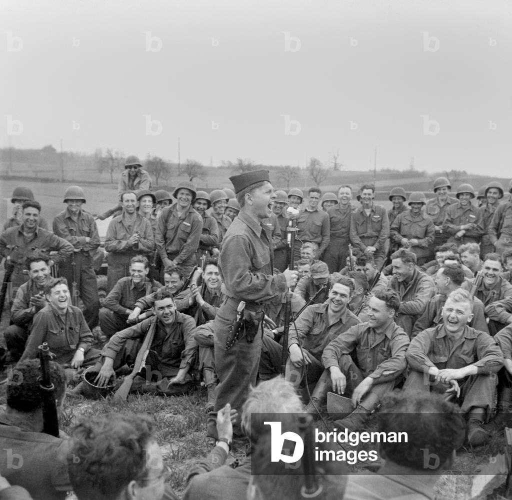 Private Mickey Rooney entertains infantry men of the 44th Division in Kist, Germany, April 13, 1945. Rooney served in the army for 21 months, entertaining troops in person and on American Forces Network radio
