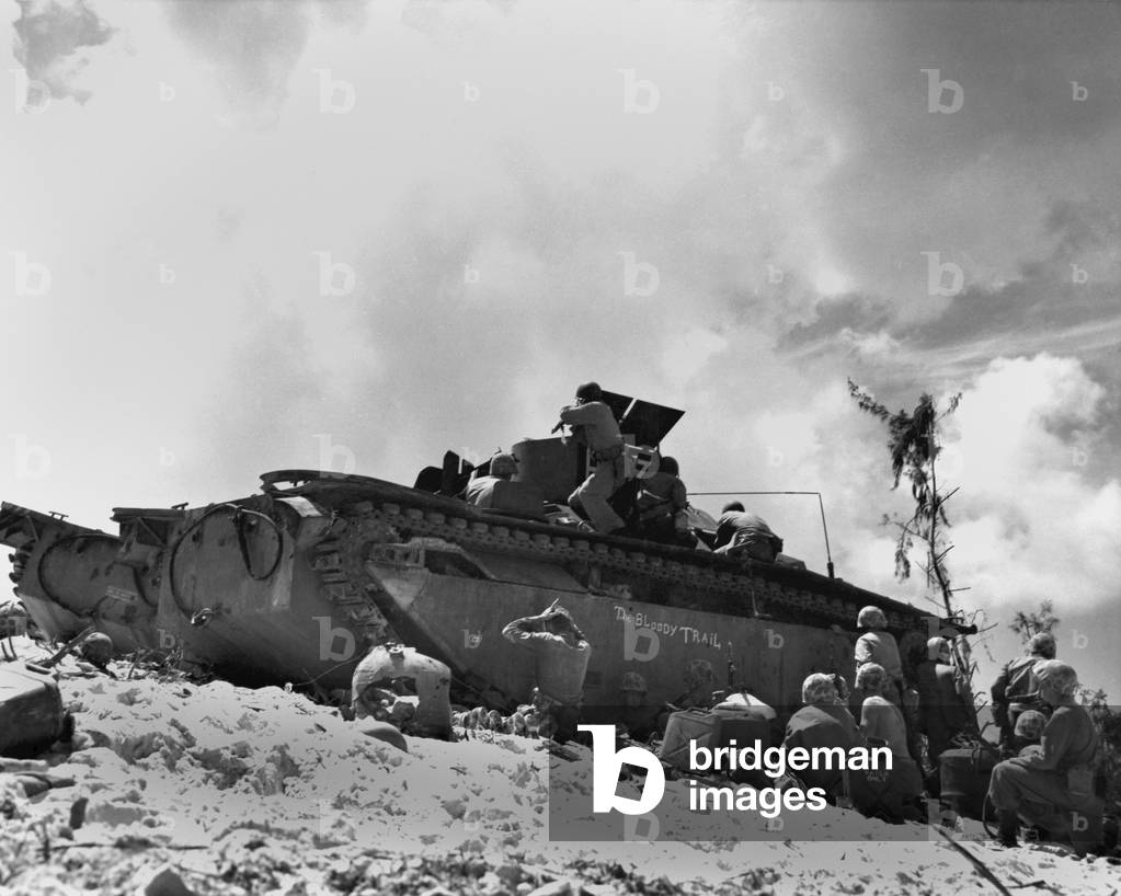 Marines fight from the shelter of an amphibious tractor on the beach at Peleliu, Sept. 14, 1944. Riflemen atop the vehicle fire at Japanese while their comrades get a breather. The AMTRAC is named 'The Bloody Trail'. World War 2, Pacific Ocean