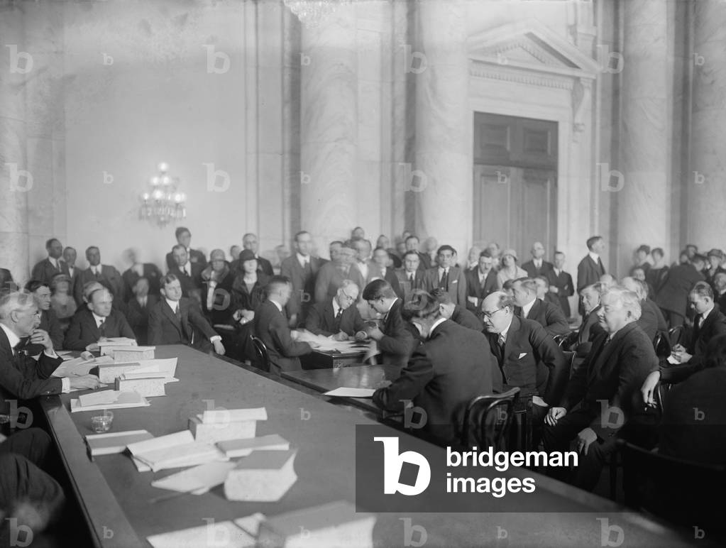 Harry F. Sinclair (1876-1956), at mid right, bent forward, with glasses, and Senator Thomas Walsh (far left, behind table), at the Senate Committee on Public Lands and Surveys investigation of the Teapot Dome scandal. March 1924