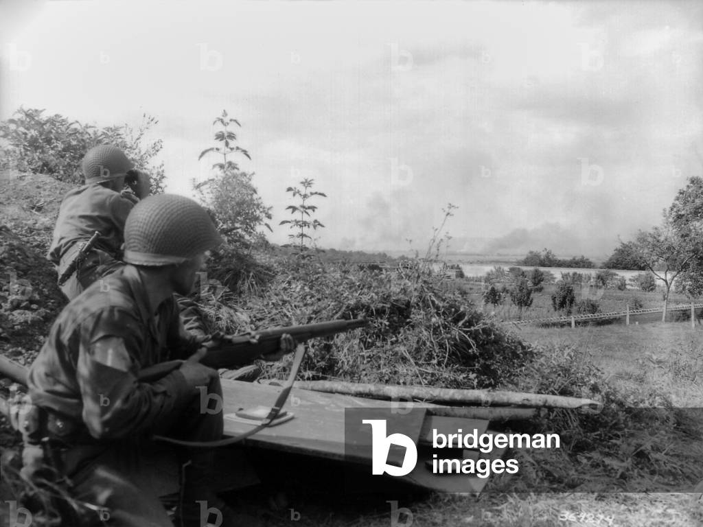 Two U.S. soldiers observe smoke from the Battle of the Falaise Pocket. They were on a reconnaissance patrol, behind the Castle of Bourg St. Leonard. Location is on the southwest edge of the pocket encircling 150,000 German soldiers. August 12-20, 1944, Normandy, France, World War 2