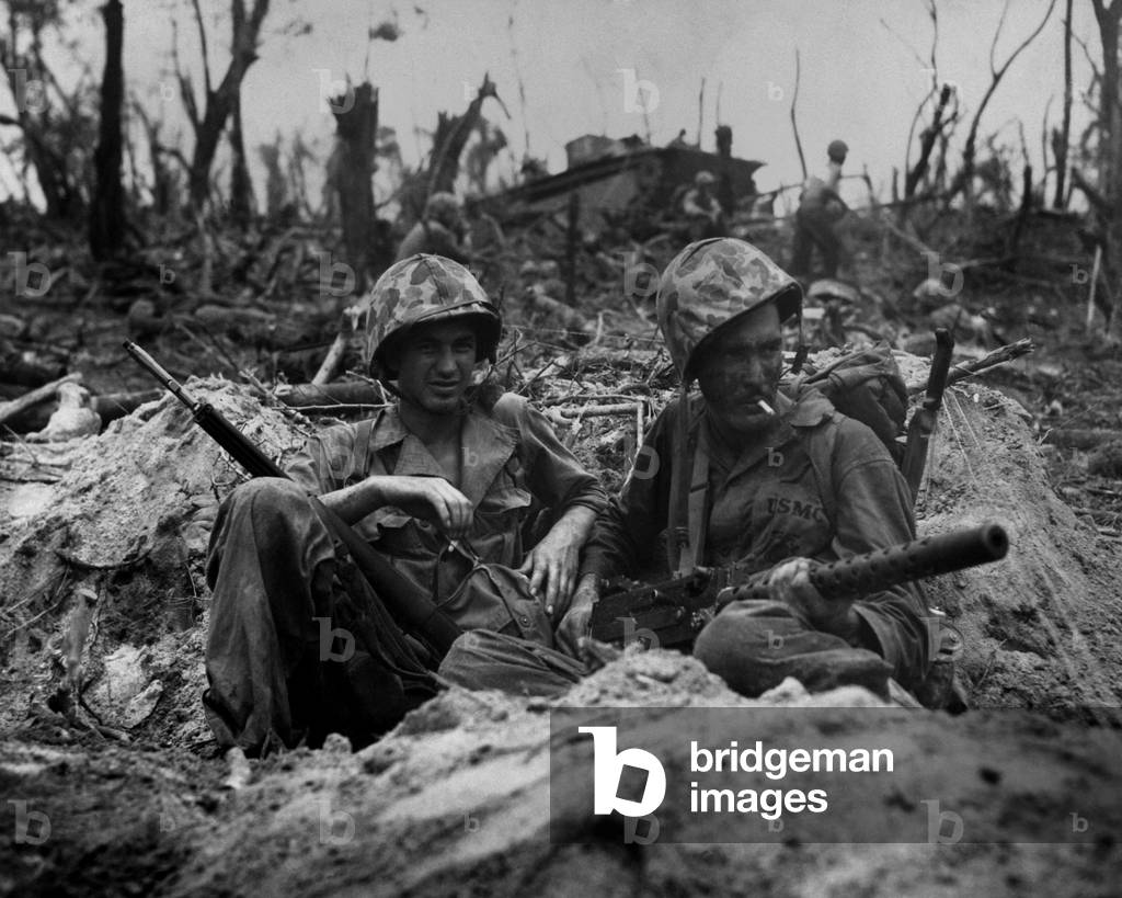 Marines smoke cigarettes, but keep their weapons close in a blasted landscape of Peleliu Island. Sept. 1944. World War 2, Pacific Ocean