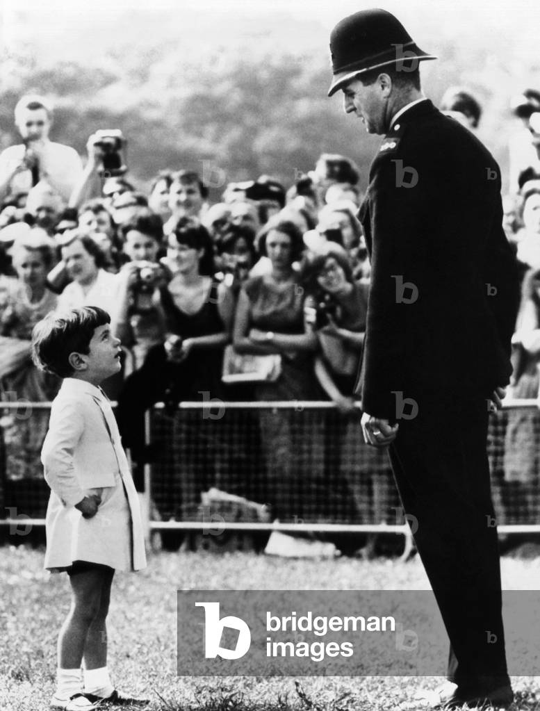 John F. Kennedy Jr. looks up at a British policeman during dedication ceremonies of a memorial to the late President Kennedy, at Runnymede, England. May 14, 1965