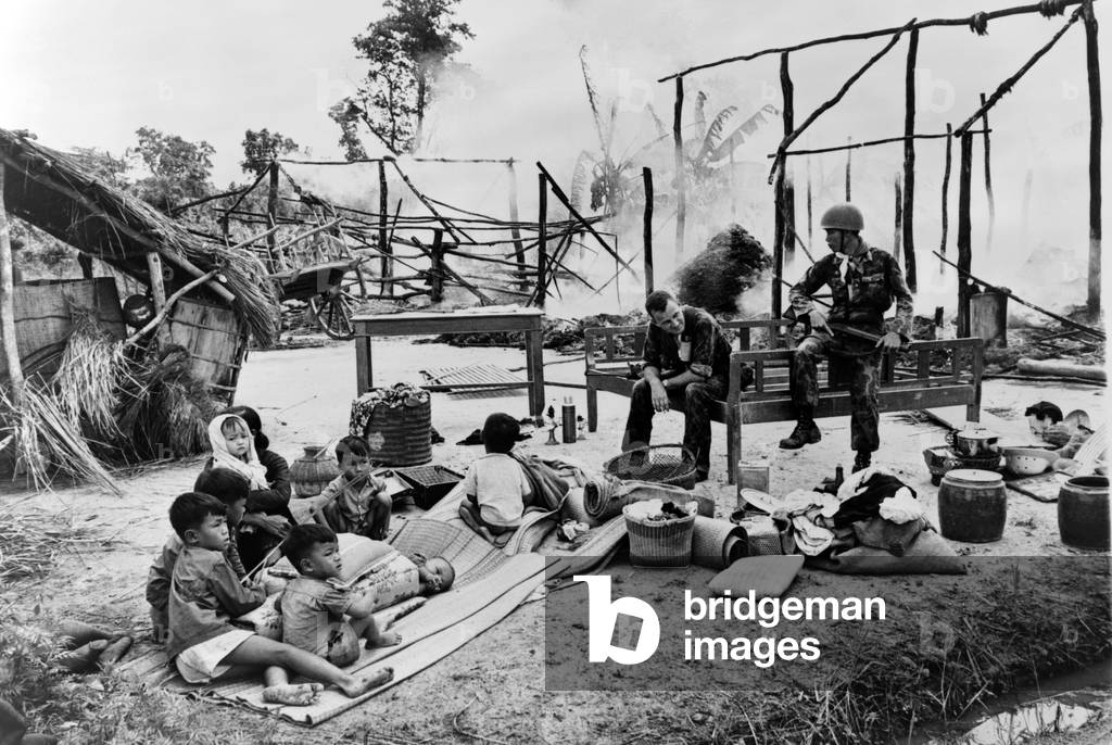Guerre Du Vietnam: South Vietnamese woman and children sit amid ruins of their village, burned by government troops on suspicion of being a Viet Cong stronghold.