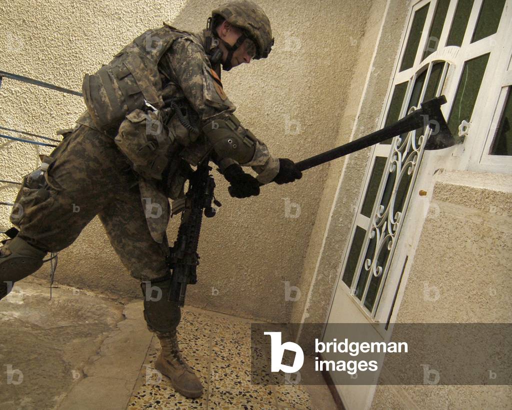 US soldier breaks down a door during a house-to-house search for illegal weapons and explosives in the Sadiyah section of Baghdad Iraq. May 6 2007