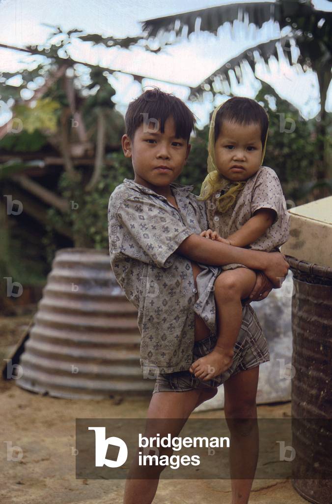 Vietnam War, Camp Campbell, Phu Bai, Republic of Vietnam. A Vietnamese boy carries a young child, c.late 1960s