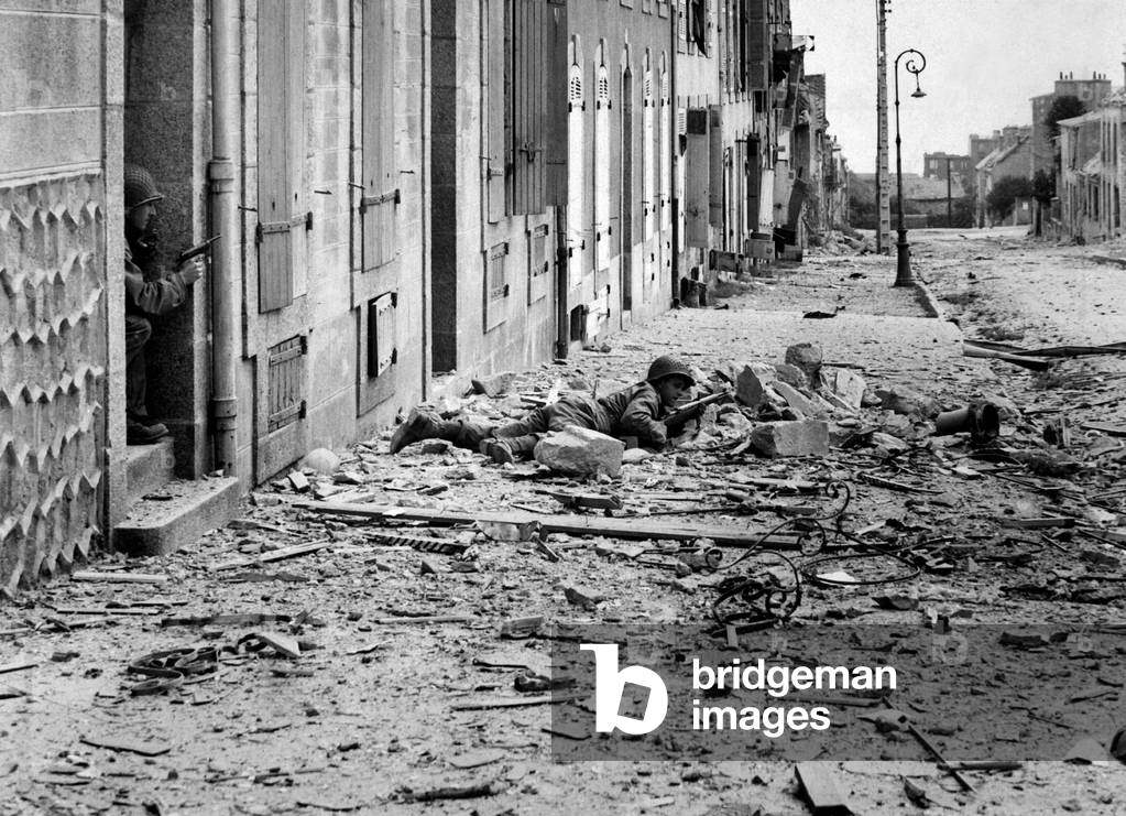 U.S. soldiers in street fighting during the Battle of Brest, in Brittany, France. One soldier looks for German snipers in the streets of Brest, while a another covers him from behind a doorway. Sept. 1944. World War 2