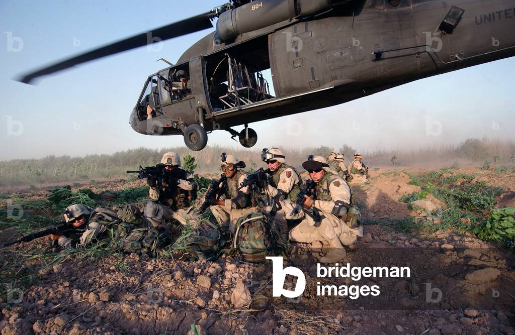 A Quick Response Force brace themselves in a security posture after being dropped off by a Black Hawk helicopter on a mission in Iraq. June 19 2004
