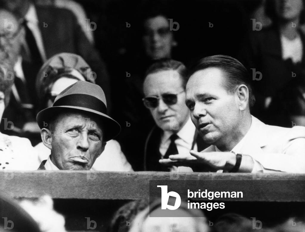 Singer Bing Crosby (1903-1977), tennis champion Jack Kramer, watching the Emerson-Ralston semi-finals match, Wimbledon, England, June 30, 1965.