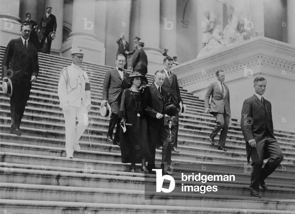 President Calvin Coolidge and the First Lady leave the Capitol after Warren Harding funeral. August 8, 1923. President Coolidge wore a formal suit with silk edging, while some near him are wearing standard business suit