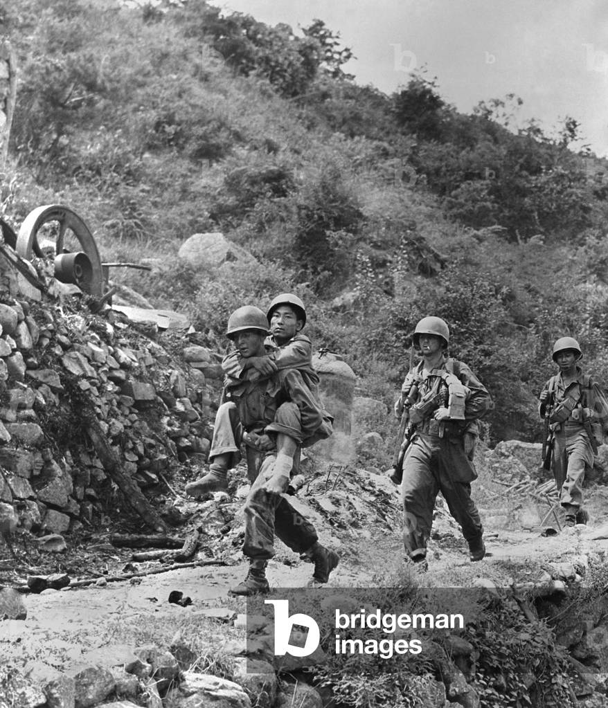 Wounded South Korean soldier carried to a first aid station by a U.S. infantryman. Korean War, 1950-53,