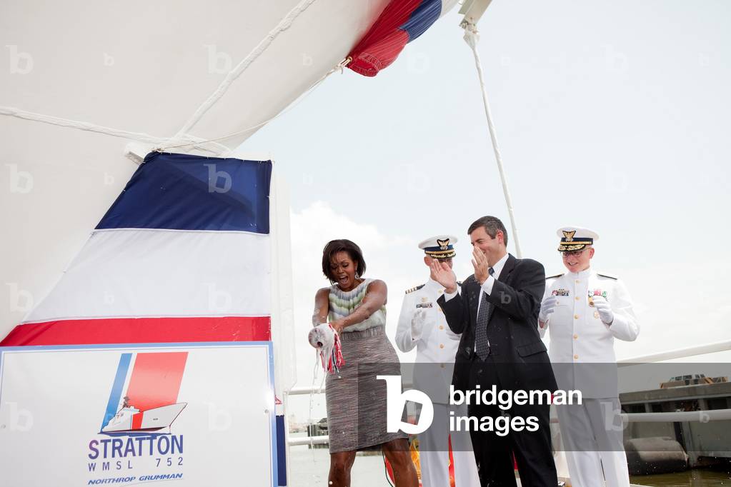Michelle Obama christens the US Coast Guard Cutter Stratton with a bottle of champagne during a ceremony at the Port of Pascagoula in Pascagoula Mississippi. Michelle wears a sheath dress of tonal striped mousseline with a skirt of layers shimmer organza boucle by Peter Soronen. July 23 2010.,