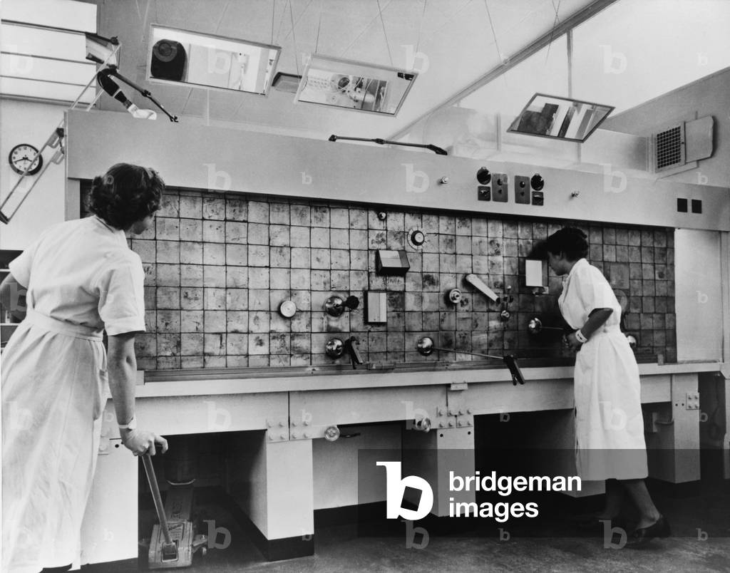Peaceful use of atom. Two female technicians prepare radioactive isotopes for medical and industrial use. They work with remote controls and are shielded by a lead barrier, at the Radiochemical Center, in Amersham England