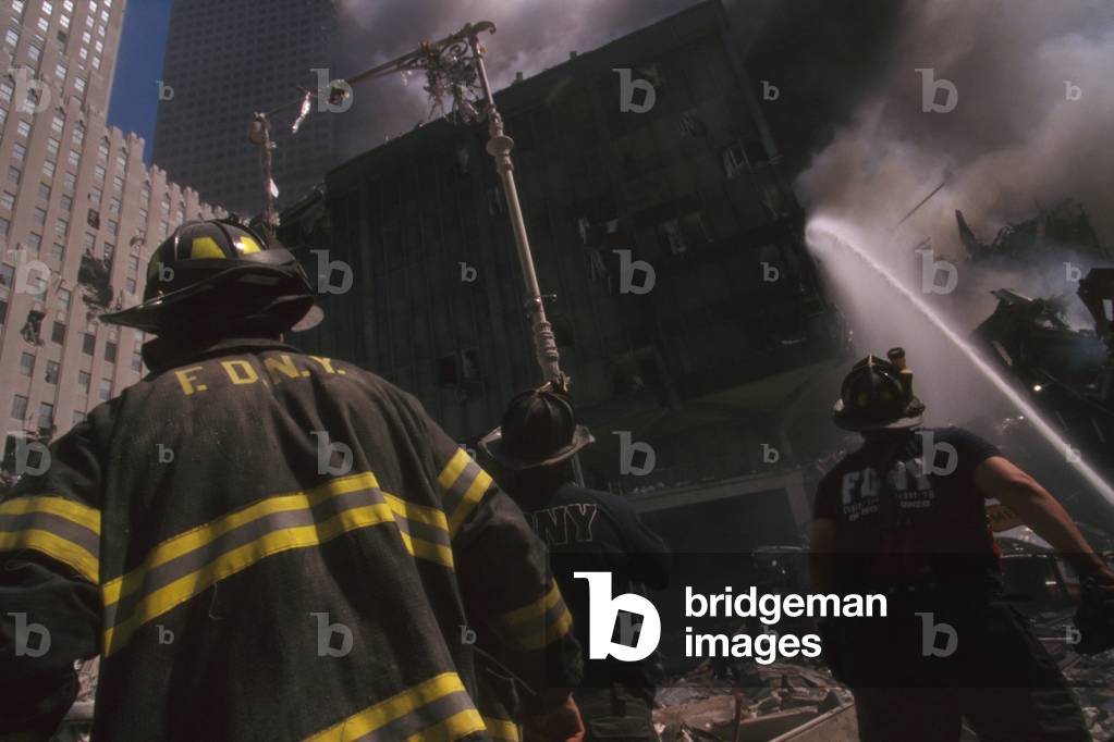 Fire fighter at World Trade Center site following September 11th terrorist attack. The stream water is to the still standing WTC 6. At left is the New York Telephone Company Building, damaged but repairable