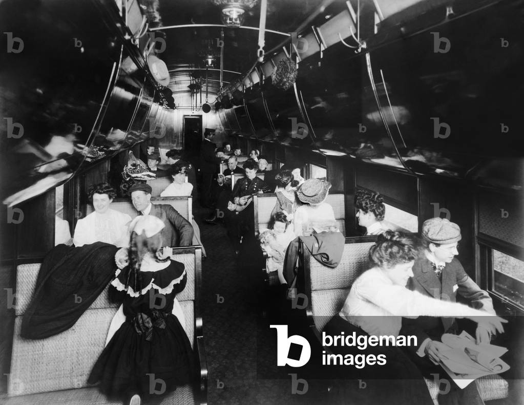 Passengers in an American Pullman railroad car in 1905. At the car's rear are two African American Pullman porters. LC-USZ62-100217