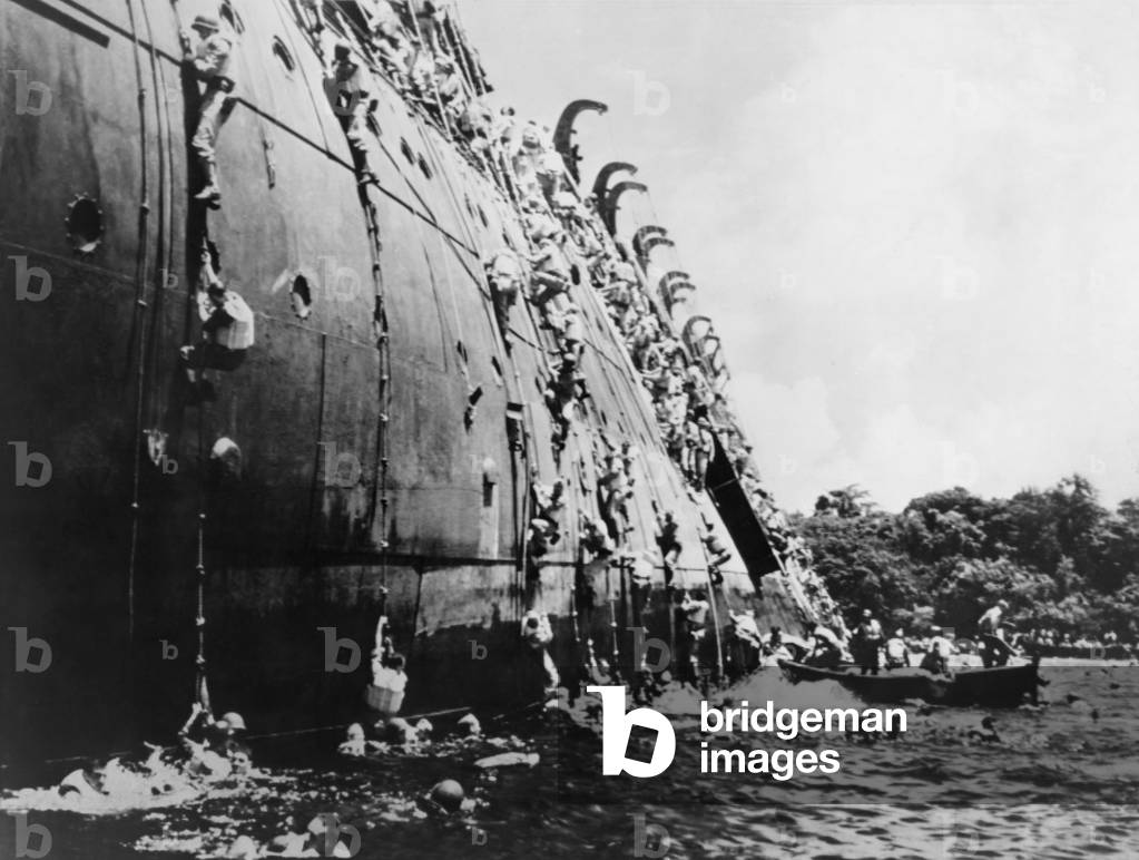 Soldiers abandoning the sinking SS President Coolidge in Espiritu Santo Harbor. She hit a U.S. mine because instructions for safe entry into the harbor were omitted from her sailing orders. All but two on board survived, but the loss of equipment and supplies deepened the crisis at Guadalcanal. Oct. 26, 1943. World War 2