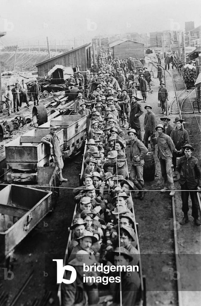 Dozens of men in open railroad cars on their way into the underground mines in Idaho in 1909