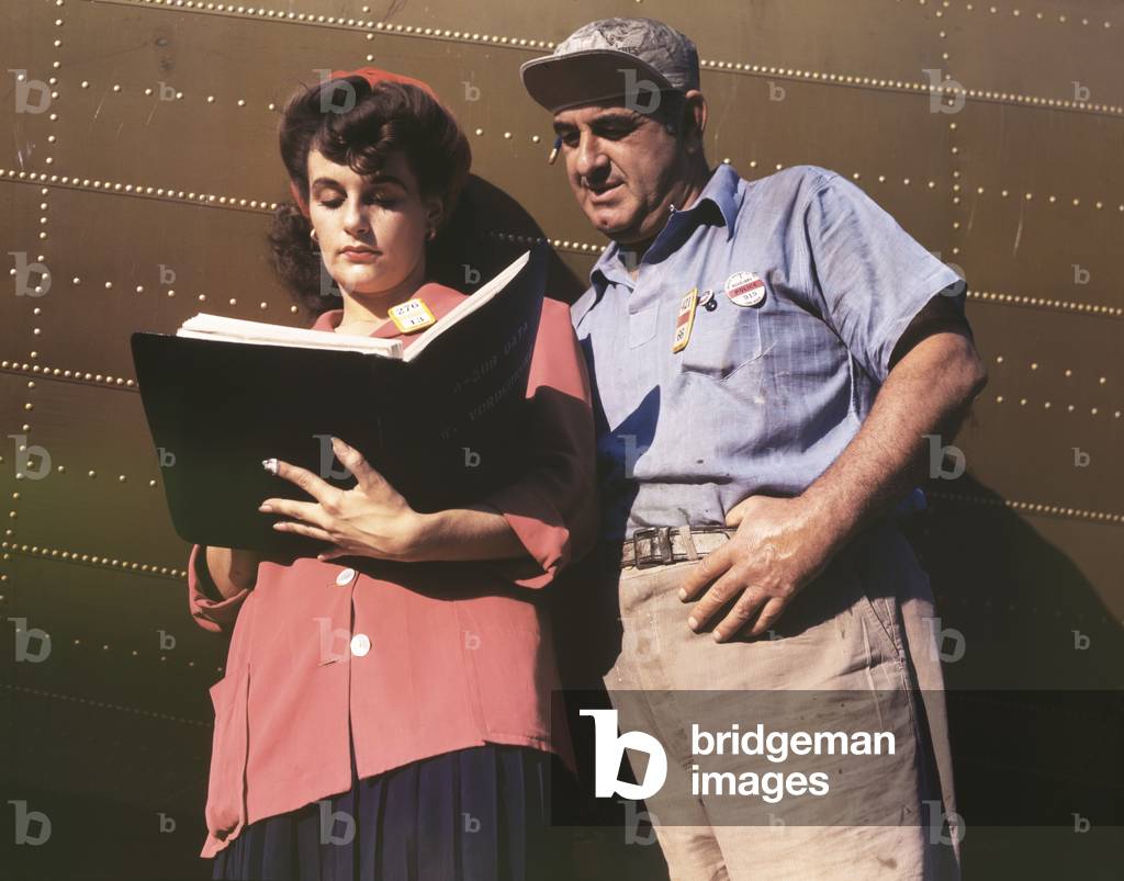 Female inspector confers with a co-worker when checking the center wings for C-47 transport planes. During World War 2, c. 1942-45