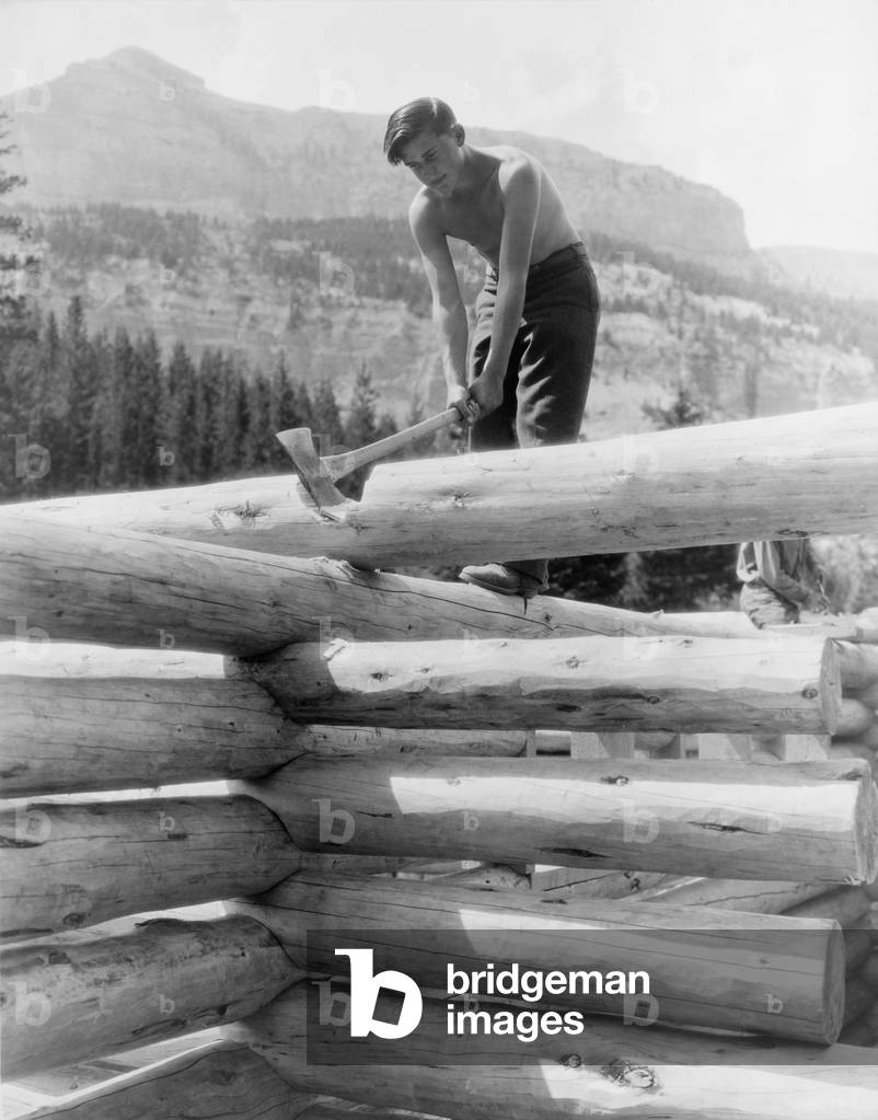 Civilian Conservation Corp worker cutting a coped joint on log cabin at Granite Creek, Teton National Forest, Wyoming in 1937