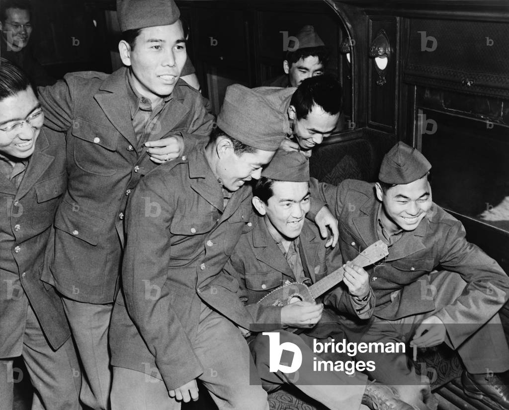 Japanese American soldiers enjoy the music of a Hawaiian ukulele as they wait to detrain at Camp Shelby, Mississippi in 1943. While some Japanese volunteered for military service, a significant and often under reported umber choose to not to