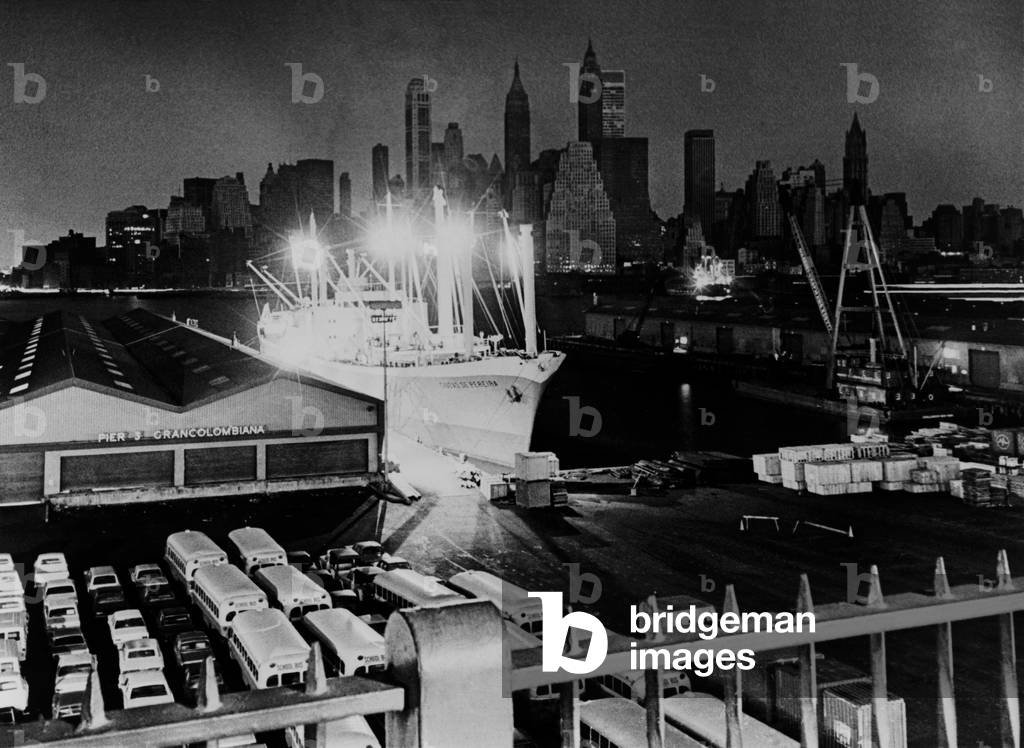New York City's Manhattan's skyline shrouded in darkness, is offset by the lights of a freighter at a Brooklyn pier. On November 9, 1965, the lights went out for 12 hours in the Northeast States and Canada