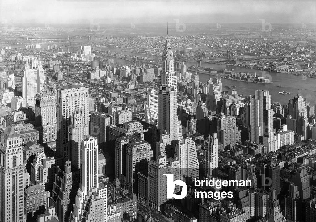 Northeast view from NYC's Empire State Building includes the Chrysler Building. Jan. 19, 1932. In mid-distance is the Queensboro Bridge over the East River, and beyond that is the borough of Queens, and the Long Island Sound. Photo by Samuel H. Gottscho