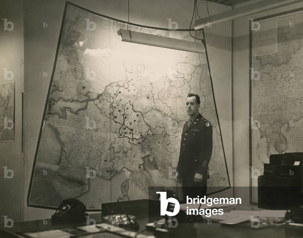 White House Map Room, c. 1943. U.S. Army Signal Corps Officer Al Cornelius stands between maps of the European and Pacific War theaters. World War 2