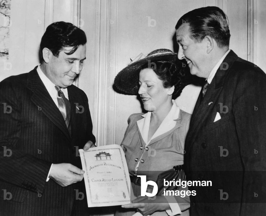 Author Pearl Buck presents Wendell Willkie with a United China Relief Fellowship Certificate. United China Relief was founded in 1941 in NYC to raise funds to aid the Chinese people during World War II. At right is James G. Blaine