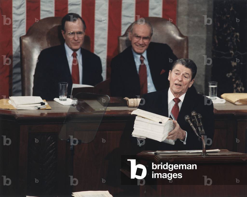 President Reagan delivering his last State of the Union address. Reagan displayed a 43 pound 'behemoth' the Federal budget and called for a 'drastic overhaul' of the budget process. Behind Reagan are VP George Bush and Speaker Jim Wright. January 25 198. PO-USP-USC-Reagan_NA-12-0091M