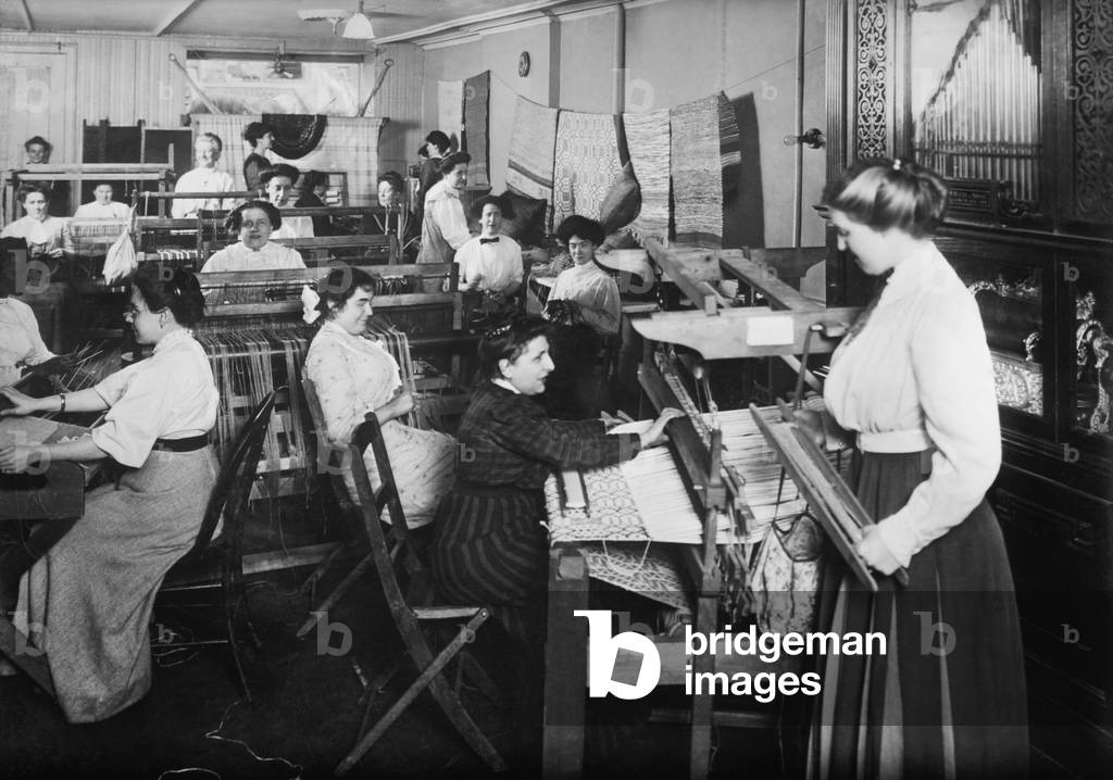 Blind women weaving at looms accompanied by an orchestrion, a self playing musical instrument, at right. Photo taken by Byron Company for the New York Association for the Blind