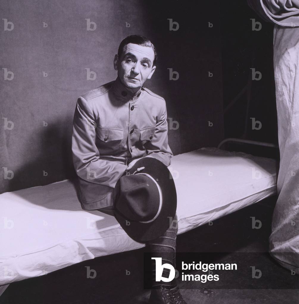 Irving Berlin (1888-1989) in WWI army uniform and seated on cot. In 1942, for he created an all soldier revue, THIS IS THE ARMY, to boost morale and raise money for the war effort