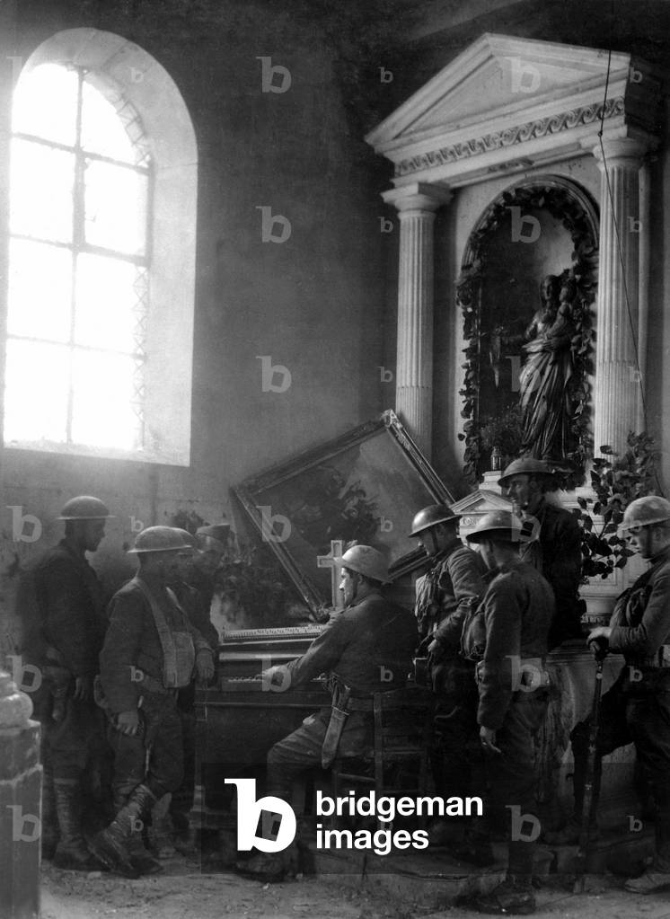 American World War I soldiers listen as one of their comrades plays the organ in the half-wrecked old church in Exermont, in the Argonne. Oct. 11, 1918