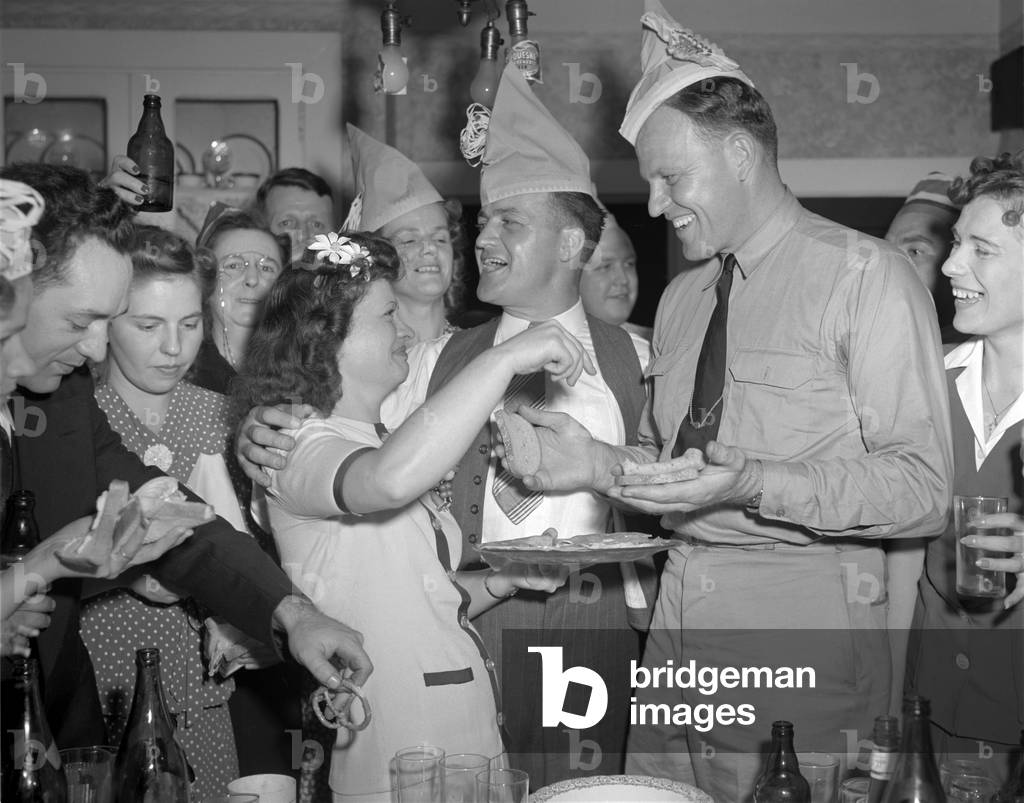 World War II, George Woolslayer (center), soldier and sailor with a party at his home, friends, relatives and fellow workers made up the list of guests, Mrs. Woolslayer (left of center) helps Chief Evans (right), to a sandwich, Pittsburgh, Pennsylvania, photograph by Alfred T. Palmer, August, 1942