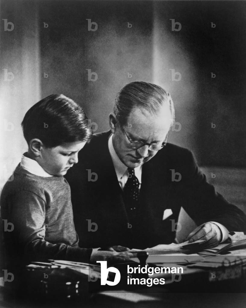Ambassador to Great Britain, Joseph Kennedy, in his London study, helping his youngest son, Edward Kennedy, with his studies. c. 1938