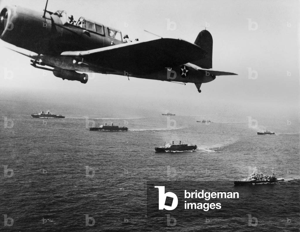 American military convoy in the South Atlantic Ocean. A U.S. Vindicator Scout bomber flies anti-submarine patrol over the convoy. Nov. 27, 1941, less than two weeks before the U.S. entered World War 2