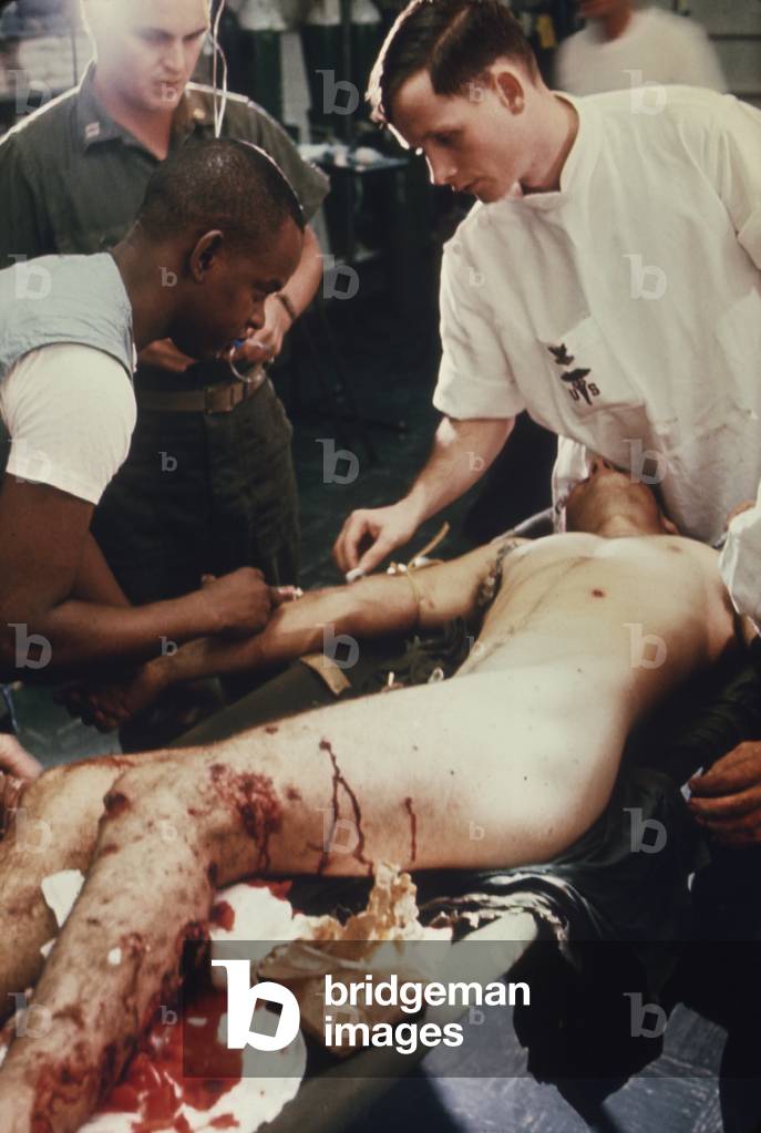 Vietnam War. US Marine Corporal is given treatment in the shock and resuscitation ward of the amphibious assault ship USS Tripoli. He was evacuated from a beach combat area by helicopter after his legs sustained heavy shrapnel wounds. July 1968